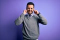 Handsome businessman with beard wearing casual tie standing over purple background covering ears with fingers with annoyed Royalty Free Stock Photo