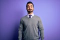 Handsome businessman with beard wearing casual tie standing over purple background puffing cheeks with funny face