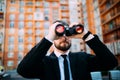 Handsome Businessman with binoculars spying on competitors outdoors