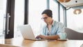 Handsome businessman in casual wear and eyeglasses is using a laptop in cafe Royalty Free Stock Photo