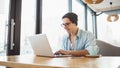 Handsome businessman in casual wear and eyeglasses is using a laptop in cafe Royalty Free Stock Photo