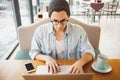 Handsome businessman in casual wear and eyeglasses is using a laptop in cafe Royalty Free Stock Photo