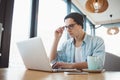 Handsome businessman in casual wear and eyeglasses is using a laptop in cafe Royalty Free Stock Photo