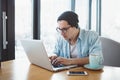 Handsome businessman in casual wear and eyeglasses is using a laptop in cafe Royalty Free Stock Photo