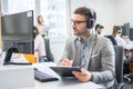 Handsome businessman checking data from computer and writing it to clipboard Royalty Free Stock Photo