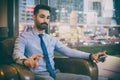 Handsome businessman with concentrated thoughtful face sitting in comfortable office chair and holding smart phone. Royalty Free Stock Photo