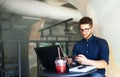 Handsome businessman distracted from work on the laptop watching video on smartphone. Freelancer holding mobile phone Royalty Free Stock Photo