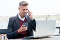 Handsome businessman drink coffee talking on phone and using computer for business online in internet cafe, busy