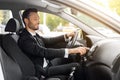 Handsome businessman driving car to airport, turning on music Royalty Free Stock Photo