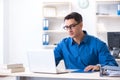 The handsome businessman employee sitting at his desk in office