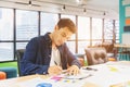 Handsome businessman in eyeglasses is making notes and smiling while working with a laptop at home Royalty Free Stock Photo