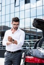 handsome businessman in eyeglasses rolling sleeves of white shirt near car trunk Royalty Free Stock Photo