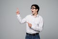 Handsome businessman in formal suit is pointing away, looking at camera and scream, on gray background Royalty Free Stock Photo