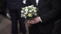 Handsome businessman holding flowers. Groom in a suit holding a bouquet of flowers. Wedding boutonniere. Elegant man Royalty Free Stock Photo