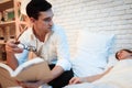 Handsome businessman holds book in his hands. Young man looks at sleeping woman in bed. Royalty Free Stock Photo