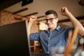 Handsome businessman with laptop having his arms with fists raised, celebrating success. Happy freelancer hipster in Royalty Free Stock Photo