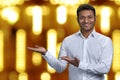 Handsome businessman looking at camera while presenting something on golden bokeh background. Royalty Free Stock Photo