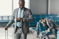 handsome businessman looking at watch while waiting for flight in airport lobby with sleeping man blurred Royalty Free Stock Photo