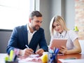 Handsome businessman and office woman working with tablet on a blurred background. Office meeting concept. Royalty Free Stock Photo