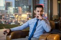 Handsome businessman with pensive face sitting in comfortable office chair and holding smart phone. Royalty Free Stock Photo