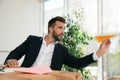 Handsome businessman playing with paper plane at desk in office Royalty Free Stock Photo