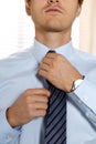 Handsome businessman preparing to official event, straighten tie Royalty Free Stock Photo