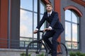 Handsome businessman riding bicycle to work on urban street in morning Royalty Free Stock Photo