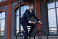 Handsome businessman riding bicycle to work on urban street in morning. Royalty Free Stock Photo