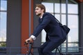 Handsome businessman riding bicycle to work on urban street in morning Royalty Free Stock Photo