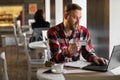 handsome businessman shopping online with credit card using laptop in cafe, young man sitting in cafe while using laptop Royalty Free Stock Photo