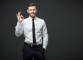 Handsome businessman showing okay sign on dark gray background.