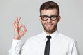 Handsome businessman showing okay sign on gray background.