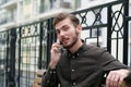 Handsome businessman sits on bench and speaks on smartphone Royalty Free Stock Photo