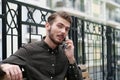 Handsome businessman sits on bench and speaks on smartphone Royalty Free Stock Photo