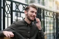 Handsome businessman sits on bench, speaks on cell phone and smiles Royalty Free Stock Photo