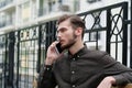 Handsome businessman sits on bench and speaks on smartphone Royalty Free Stock Photo