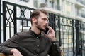 Handsome businessman sits on bench and speaks on smartphone Royalty Free Stock Photo