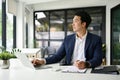 Handsome businessman sits at his office desk, looking out the window and daydreaming Royalty Free Stock Photo