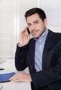 Handsome businessman sitting at desk talking on mobile. Royalty Free Stock Photo