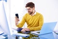 Handsome businessman sitting in the office and text messaging on his cell phone Royalty Free Stock Photo