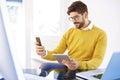 Handsome businessman sitting in the office and using cell phone and digital tablet Royalty Free Stock Photo