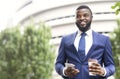 Handsome businessman standing outdoors with coffee and smartphone in arms Royalty Free Stock Photo