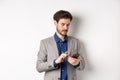 Handsome businessman in stylish suit chatting on smartphone, using mobile phone, standing on white background Royalty Free Stock Photo
