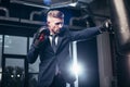 handsome businessman in suit boxing with punching bag