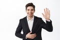 Handsome businessman in suit, corporate man waving hand and say hello, greet you, introduce himself on party, wearing Royalty Free Stock Photo