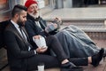 Senior caucasian beggar male telling story about life to businessman