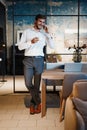 Handsome businessman in suit standing and talking on smartphone in modern office. Royalty Free Stock Photo