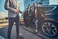 Attractive man in sunglasses is talking by smartphone and sitting in the car while his assistant is opening door for him Royalty Free Stock Photo