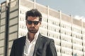 Handsome businessman with sunglasses, outdoor in the city. Charming and modern style, with shirt and suite. Cool hairstyle. Behind Royalty Free Stock Photo