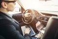 Handsome businessman talking with phone sitting with laptop on backseat of car